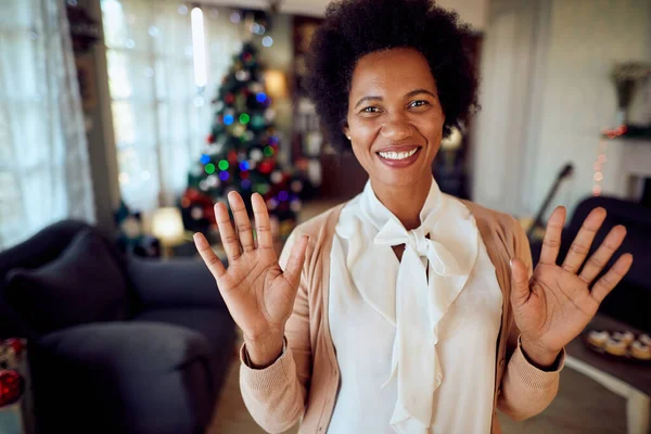 Happy African American woman waving while making video call on Christmas day from home.