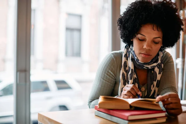 African American mid adult woman doing a research while learning at university library.