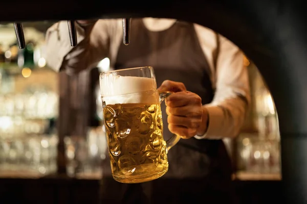 Close-up of barista pouring beer from beer tap while working in a pub.