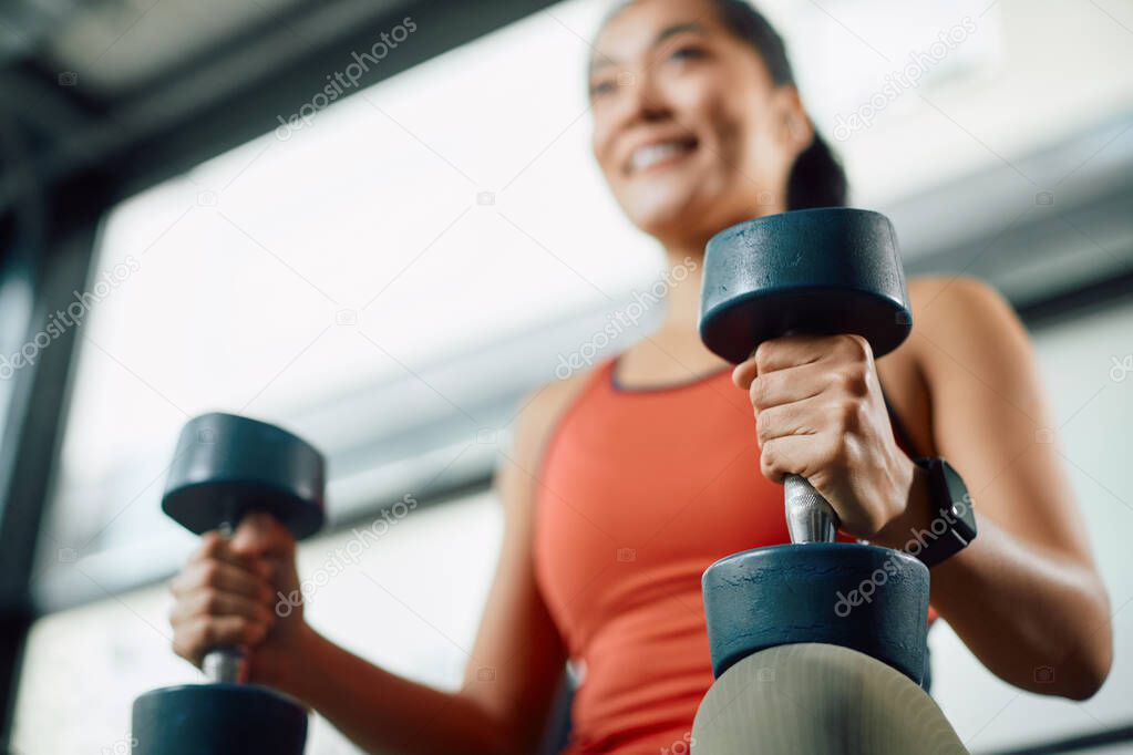 Close-up of athletic woman using dumbbells during strength training in a gym.