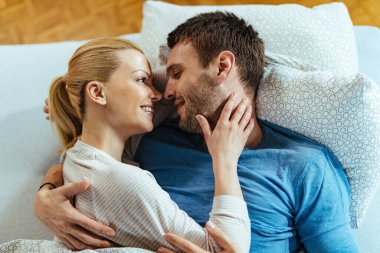 Sevgi dolu çiftin yatakta dinlenmesi ve birbirlerine şefkat göstermeleri manzarasının üstünde.. 
