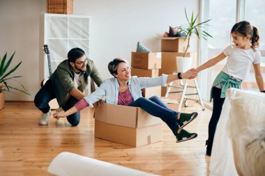 Happy parents and daughter having fun while moving into a new home. 