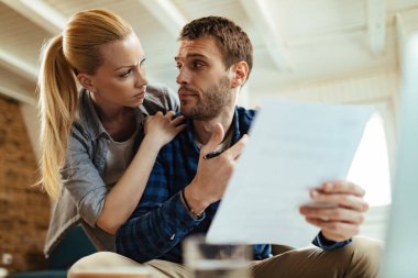Low angle view of distraught couple communicating while going through their home finances. 
