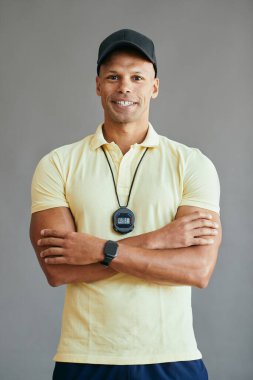 Kollarını kavuşturup kameraya bakan kendine güvenen koçun portresi..