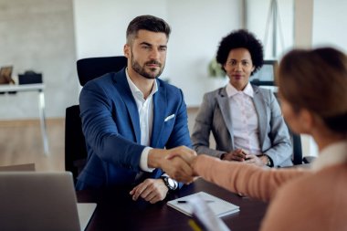 Businessman handshaking with potential candidate during a job interview in the office. 