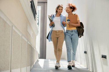 Young female students laughing and having fun while walking down the hall at the university.