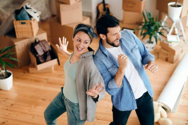 High angle view of cheerful couple dancing and having fun at their new apartment.