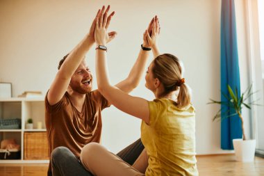 Happy athletic man and his girlfriend congratulating each other on successful workout at home. 