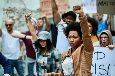 African American woman with raised fist participating in black civil rights demonstrations. 