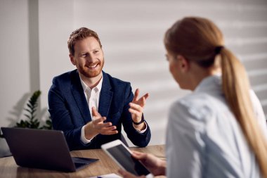 Happy entrepreneur and his female co-worker communicating during business meeting at corporate office.