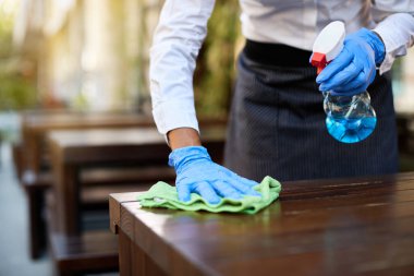 Close-up of waitress disinfecting tables at outdoor cafe during coronavirus epidemic. 