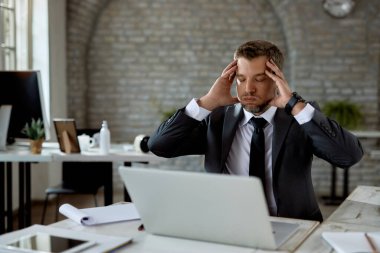 Male entrepreneur feeling stressed after receiving problematic e-mail on a computer in the office. 