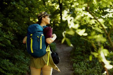 Ormanda yürürken sırtında sırt çantası taşıyan bir kadın.. 
