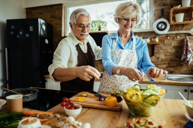 Happy senior couple preparing healthy food while cooking together in the kitchen. 