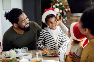 Mutlu Afro-Amerikan ailesi Noel kurabiyesi yerken yemek masasında eğleniyor. Çocuğa odaklan.. 