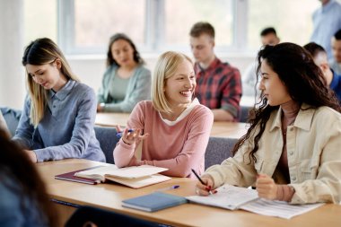 Young happy woman communicating with her female classmate during a class at the university.