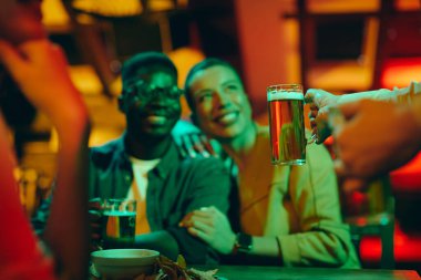 Close-up of waitress serving beer to guest while working in a pub at night. 