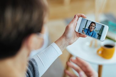 Close-up of female patient using smart phone and having video chat with her doctor. 