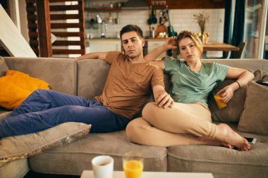Young man and his girlfriend relaxing in the living room and watching TV. 