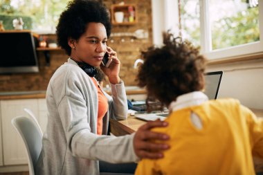 African American mother with children working at home and talking on the phone. 