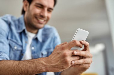 Close-up of a an texting on mobile phone while relaxing at home. 