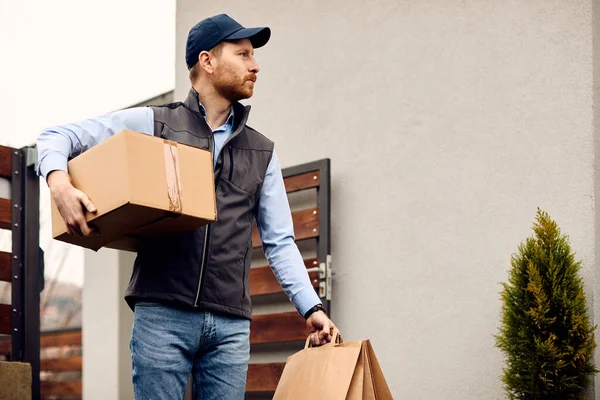 Male Courier Carrying Cardboard Box Bags While Making Home Delivery — Stockfoto