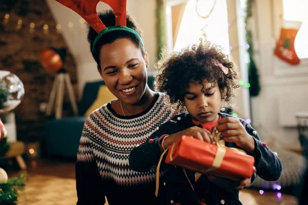 Happy African American Mother Enjoying Her Daughter Who Unwrapping Christmas — Foto Stock