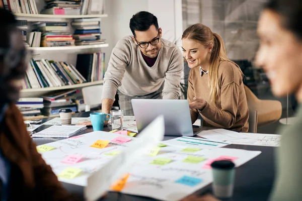 Young creative business colleagues using laptop while working on new project in the office.