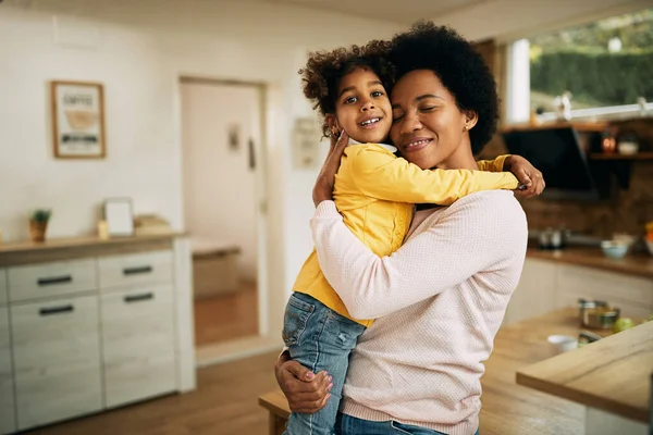 Happy black mother embracing her small daughter at home.