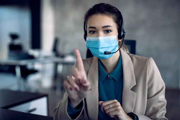 Young businesswoman having conference call in the office and wearing face mask due to coronavirus pandemic.