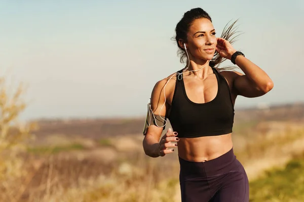 Young Muscular Build Woman Jogging While Listening Music Earphones Nature — Stockfoto