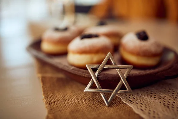 Close-up of star of David with traditional sufganiyah on plate during Hanukkah.