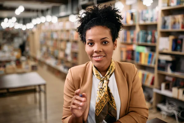Happy black female professor teaching via video call from university library.