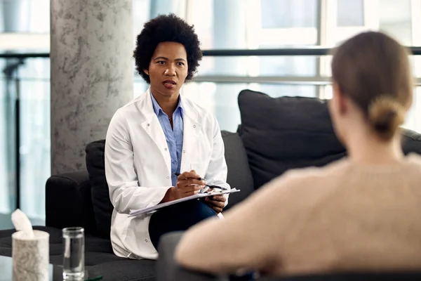 Black female psychotherapist communicating with a patient during a session at the clinic.