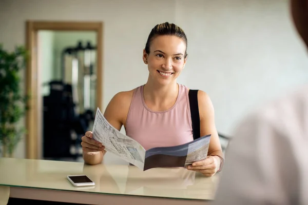 Happy Athletic Woman Reading Publication While Talking Receptionist Health Club —  Fotos de Stock
