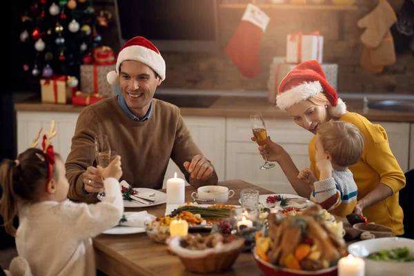 Happy family having lunch at dining table on Christmas day. Focus is on parents.