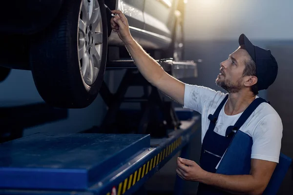 Car Mechanic Examining Tire While Working Auto Repair Shop — 스톡 사진