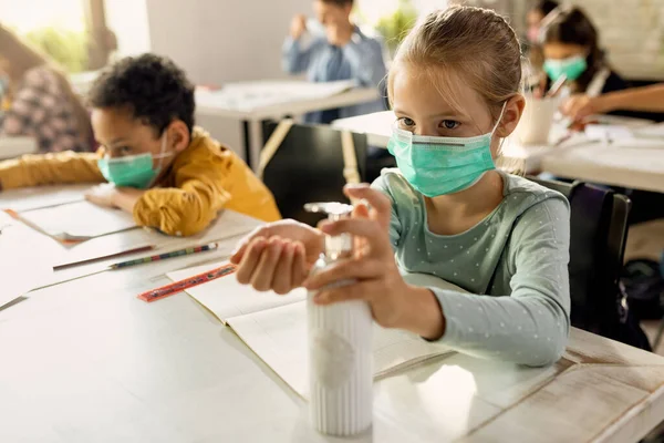 Schoolgirl Face Mask Using Hands Sanitizer While Sitting Desk Classroom — Foto Stock