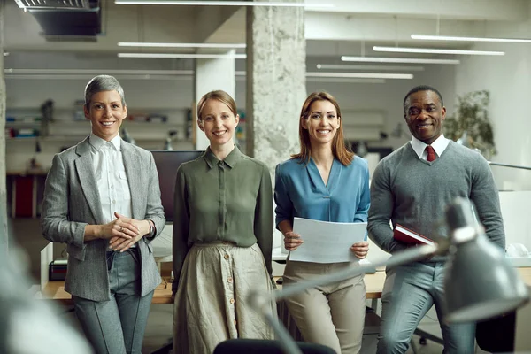 Team of happy business people working in the office and looking at camera.