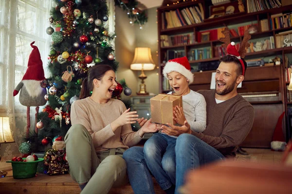 Happy parents surprising their son with Christmas present and having fun at home.