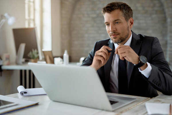 Mid adult businessman using computer while working at his office desk. 
