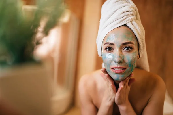 Young beautiful woman with a detox mas on her face in the bathroom.