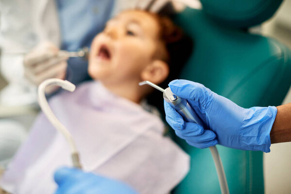 Close-up of stomatologist using dental equipment during child's dental check-up.