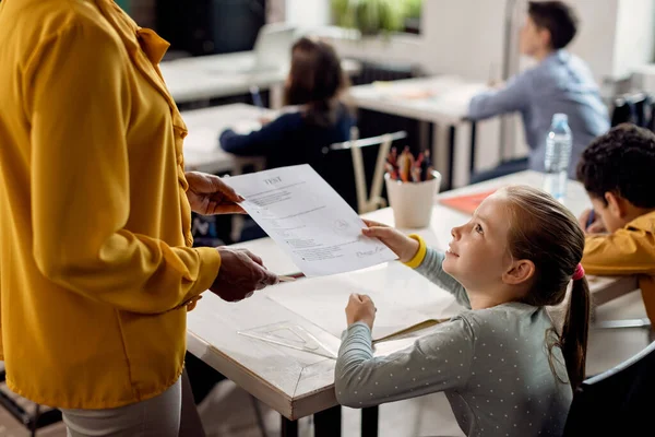 Elementary student receiving exam results on a class in the classroom.