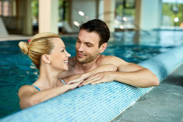 Happy couple relaxing in the water of spa\'s swimming pool at talking.