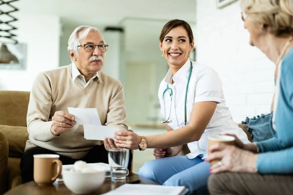 Happy Female Doctor Mature Couple Talking While Looking Photos Form — Fotografia de Stock