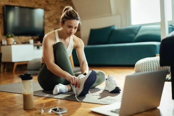 Junge Sportlerin Benutzt Laptop Beim Anziehen Ihrer Turnschuhe Wohnzimmer — Stockfoto