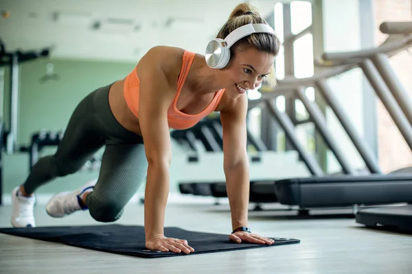Happy Athletic Woman Wearing Headphones While Exercising Floor Health Club — Stockfoto