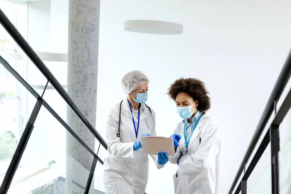 Female Healthcare Experts Face Masks Reading Medical Data While Standing — Foto de Stock