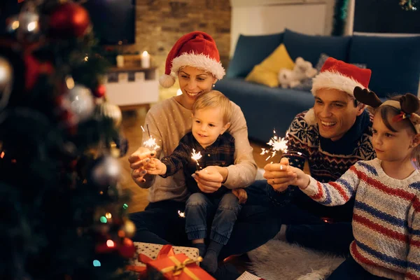 Happy Family Having Fun Sparklers While Sitting Front Christmas Tree — Zdjęcie stockowe